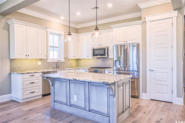 kitchen featuring appliances with stainless steel finishes, light hardwood / wood-style floors, white cabinetry, light stone countertops, and a center island