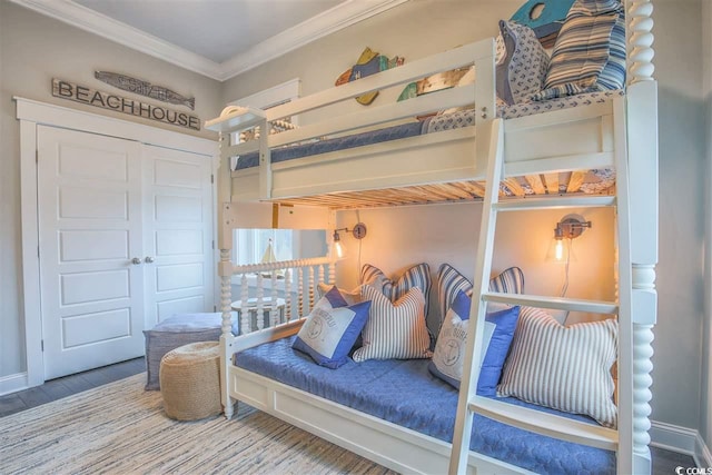 bedroom with wood-type flooring, crown molding, and a closet