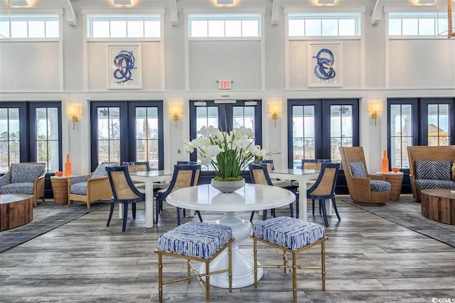 dining area with a high ceiling, hardwood / wood-style flooring, and french doors