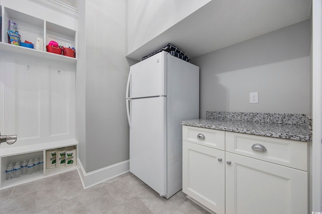 kitchen featuring white refrigerator, white cabinetry, light tile patterned floors, and light stone countertops