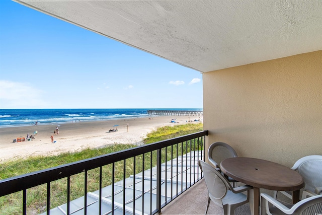 balcony featuring a water view and a beach view