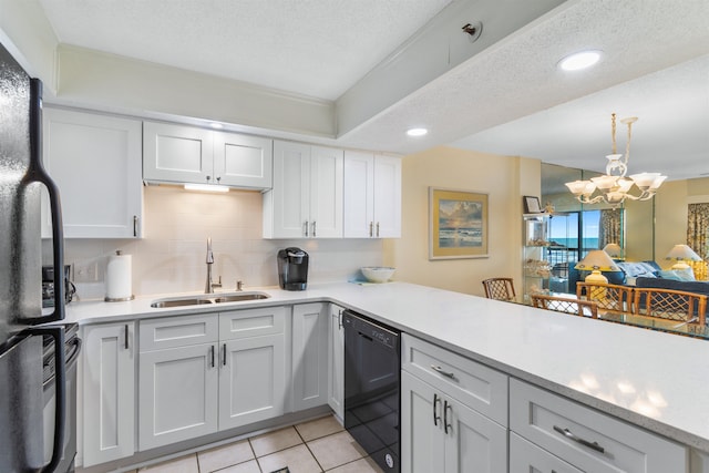 kitchen featuring sink, kitchen peninsula, a textured ceiling, black appliances, and an inviting chandelier