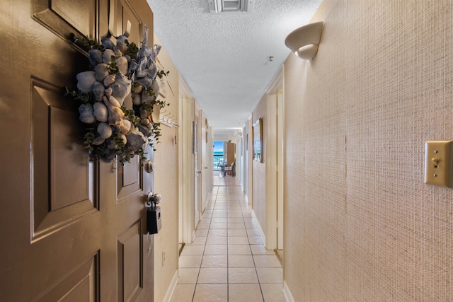 corridor featuring a textured ceiling and light tile patterned floors