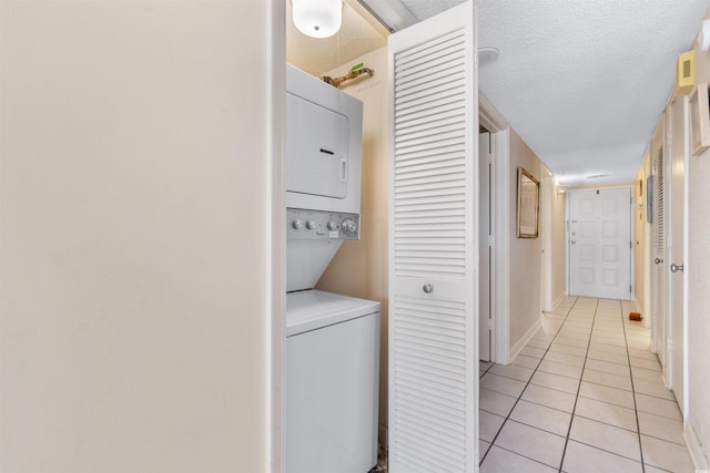 laundry room with a textured ceiling, stacked washer and dryer, and light tile patterned floors