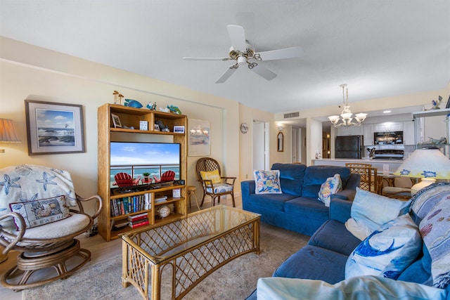 living room featuring ceiling fan with notable chandelier and light hardwood / wood-style floors