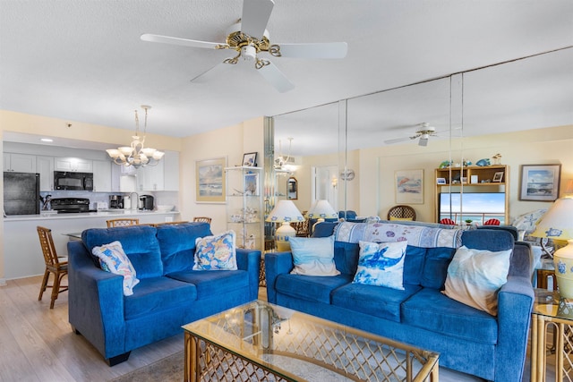 living room featuring ceiling fan with notable chandelier and light hardwood / wood-style flooring