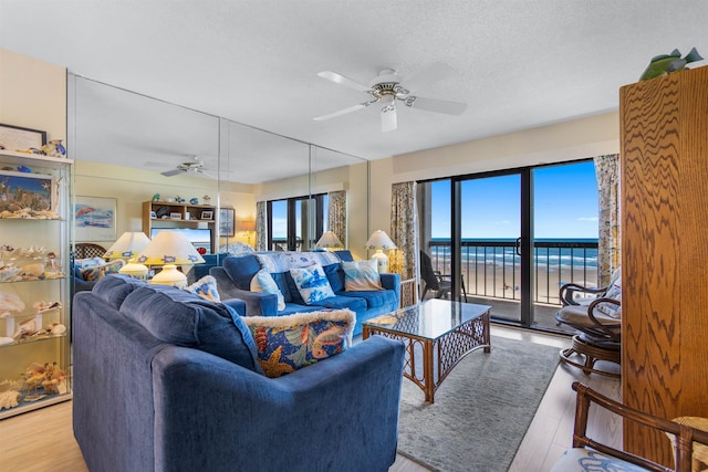 living room featuring ceiling fan, a water view, and a healthy amount of sunlight