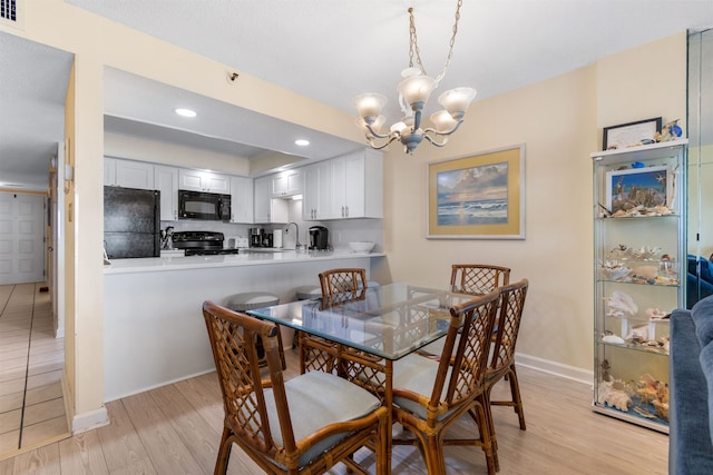 dining space featuring sink, light hardwood / wood-style flooring, and a notable chandelier