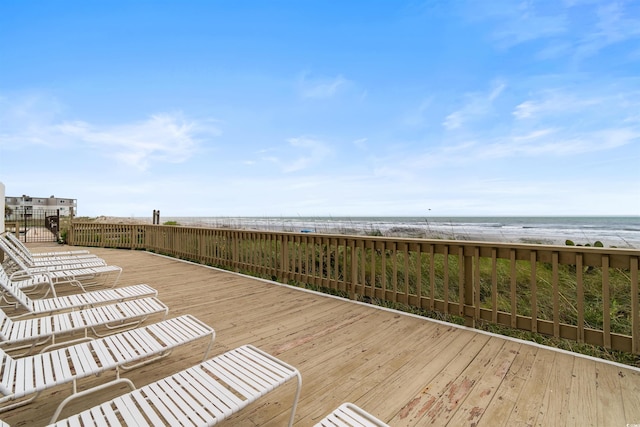 wooden terrace featuring a water view and a view of the beach