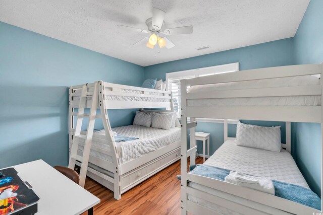 bedroom featuring ceiling fan, wood-type flooring, and a textured ceiling