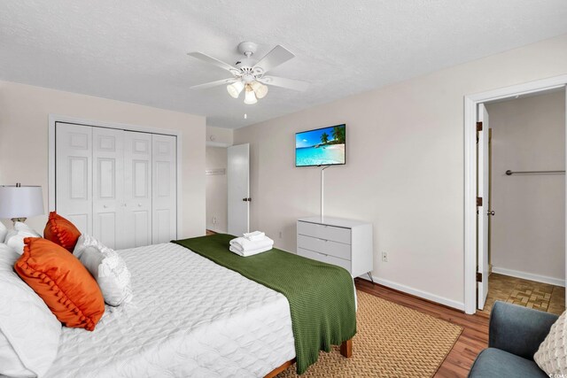 bedroom with light wood-type flooring, a textured ceiling, ceiling fan, and a closet