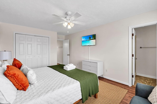 bedroom featuring a textured ceiling, a closet, wood finished floors, and baseboards