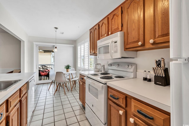 kitchen featuring white appliances, brown cabinets, decorative light fixtures, light countertops, and light tile patterned flooring