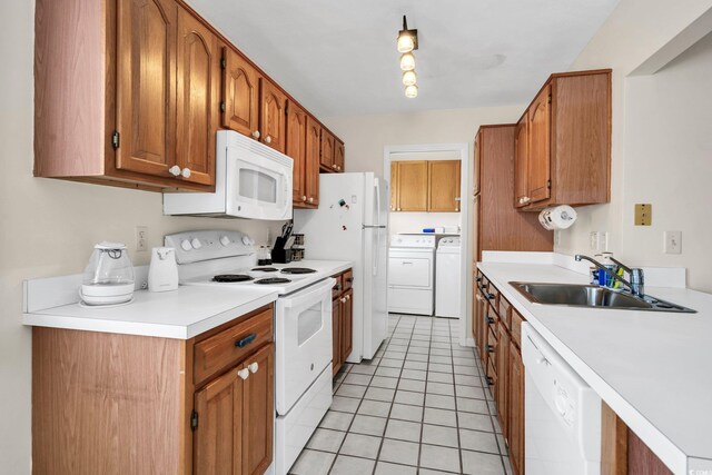 kitchen with white appliances, washing machine and dryer, sink, and light tile patterned flooring