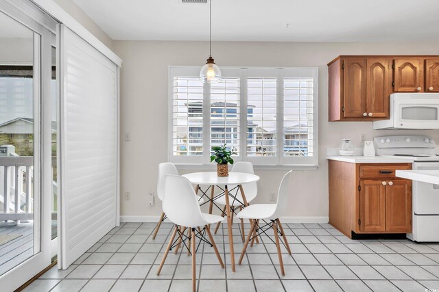 interior space with white appliances, hanging light fixtures, and light tile patterned flooring