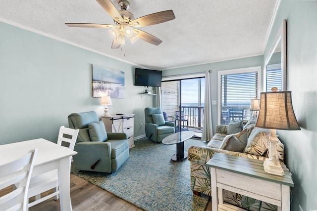 living room featuring a textured ceiling, wood-type flooring, crown molding, and ceiling fan