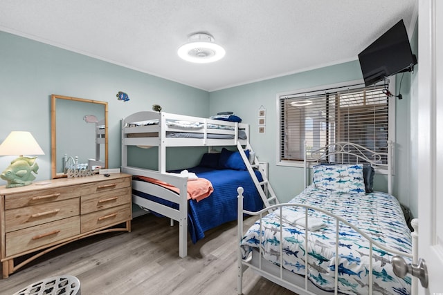 bedroom featuring a textured ceiling, crown molding, and hardwood / wood-style floors