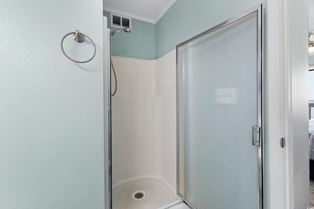 bathroom featuring a textured ceiling, a shower with shower door, and crown molding