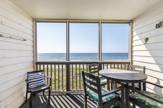 sunroom featuring a water view and a beach view