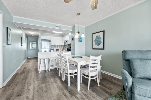 dining area featuring light wood-type flooring, a textured ceiling, ornamental molding, and ceiling fan