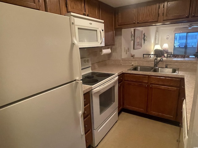 kitchen with white appliances, kitchen peninsula, and sink