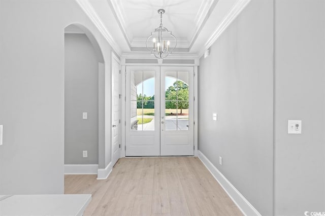 entrance foyer featuring french doors, a chandelier, light hardwood / wood-style floors, a tray ceiling, and ornamental molding