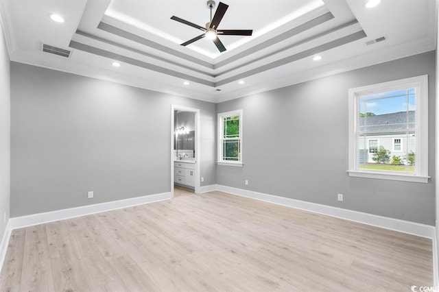 unfurnished bedroom featuring a raised ceiling, light hardwood / wood-style flooring, and ensuite bathroom