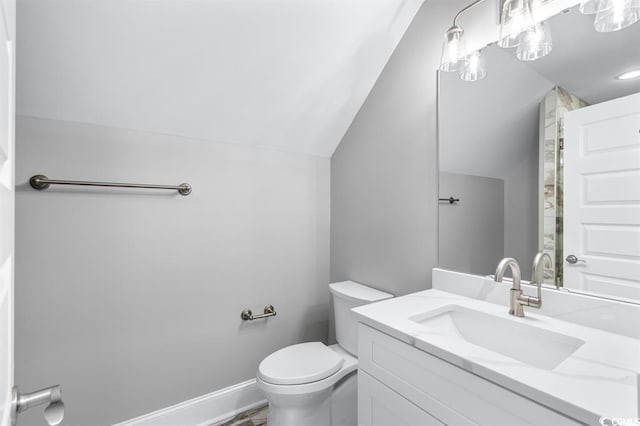 bathroom featuring vanity, vaulted ceiling, and toilet