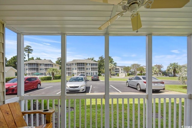 sunroom / solarium with a residential view and a ceiling fan