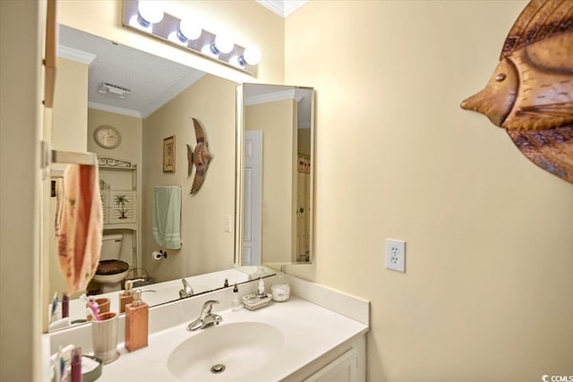 bathroom with vanity, crown molding, and toilet