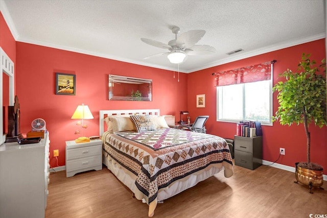 bedroom featuring baseboards, a textured ceiling, wood finished floors, and ornamental molding