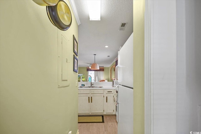 kitchen with visible vents, light countertops, freestanding refrigerator, light wood-style floors, and a sink