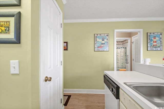 kitchen featuring a sink, crown molding, white dishwasher, and light countertops