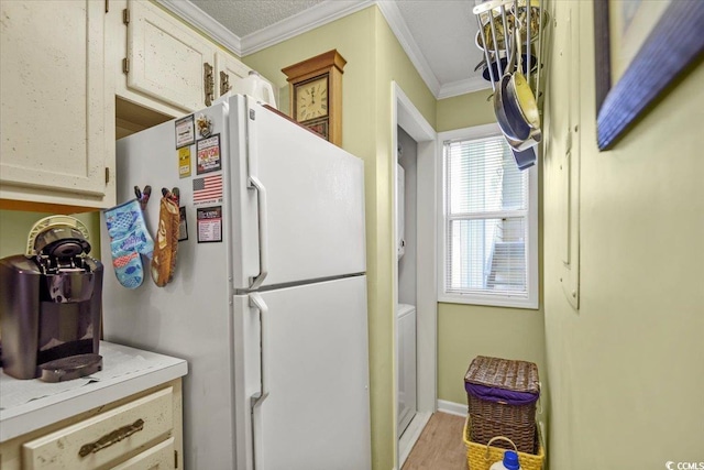 kitchen with light wood-style floors, ornamental molding, light countertops, and freestanding refrigerator