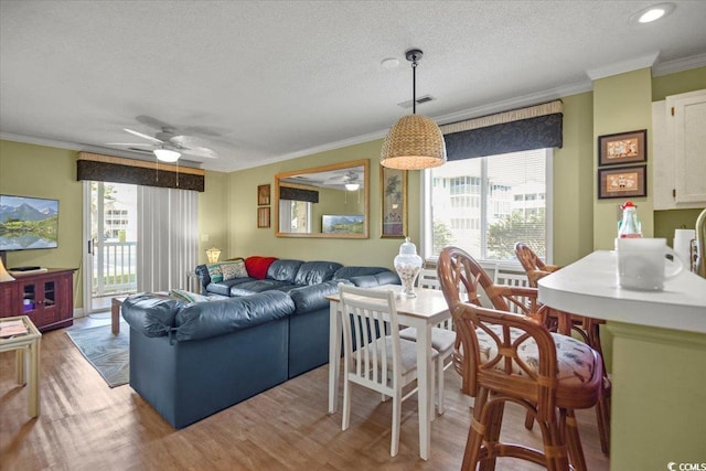 living room featuring light wood-type flooring, visible vents, a ceiling fan, and crown molding