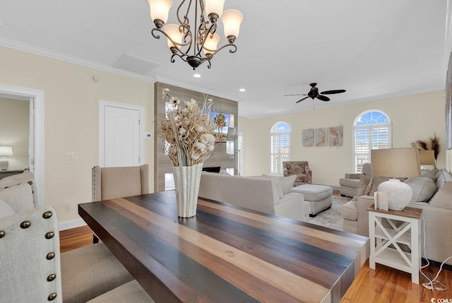 dining room featuring ceiling fan, a fireplace, wood finished floors, baseboards, and crown molding