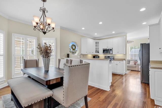 dining space with an inviting chandelier, recessed lighting, light wood-style flooring, and crown molding