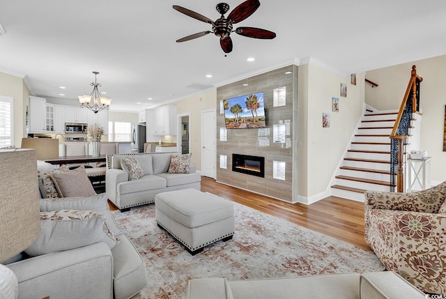 living room with recessed lighting, light wood-type flooring, a tile fireplace, and crown molding