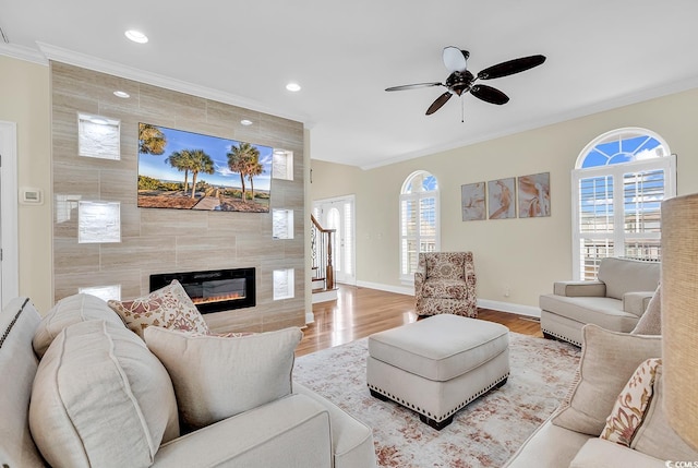 living room featuring plenty of natural light, ornamental molding, and a tiled fireplace