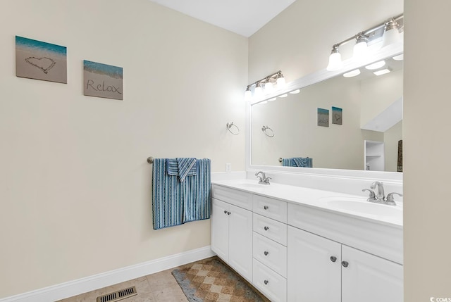 full bath with double vanity, baseboards, visible vents, and a sink