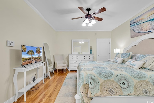 bedroom featuring a ceiling fan, crown molding, light wood-style flooring, and baseboards