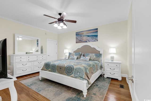 bedroom featuring crown molding, visible vents, a ceiling fan, wood finished floors, and baseboards