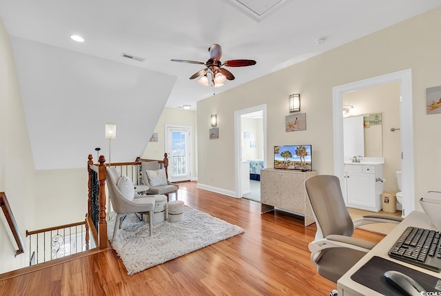 office featuring visible vents, light wood-style flooring, attic access, a sink, and baseboards