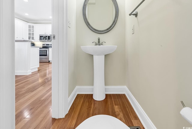 half bath with toilet, baseboards, wood finished floors, and recessed lighting