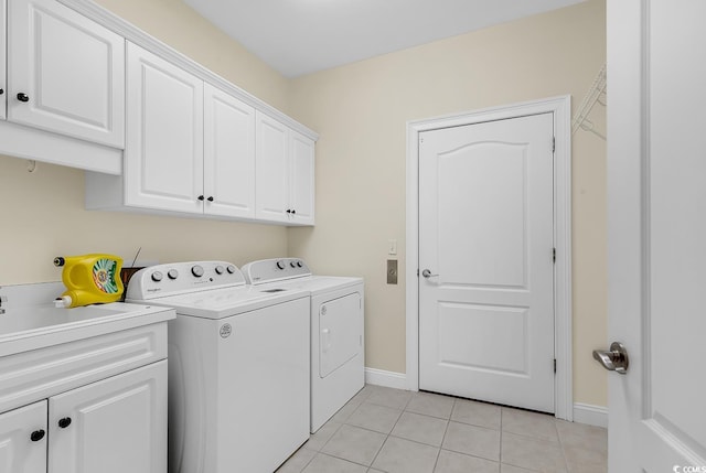 laundry room with washing machine and dryer, cabinet space, baseboards, and light tile patterned floors