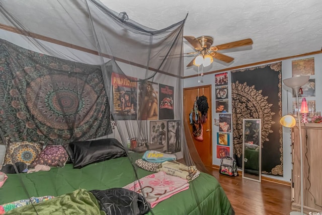 bedroom with a textured ceiling, crown molding, ceiling fan, and dark hardwood / wood-style flooring