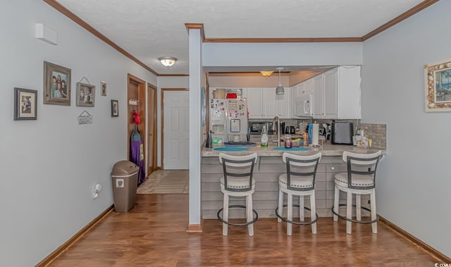 305 Resort Dr Unit C12, Myrtle Beach, SC 29588 - kitchen featuring white appliances, crown molding, white cabinets, a breakfast bar, and wood finished floors