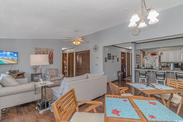 living room featuring ceiling fan with notable chandelier, dark wood-type flooring, and vaulted ceiling