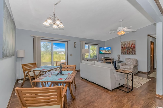 interior space with a wealth of natural light, ceiling fan with notable chandelier, wood-type flooring, and lofted ceiling