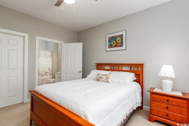 bedroom featuring ceiling fan, light colored carpet, and ensuite bath